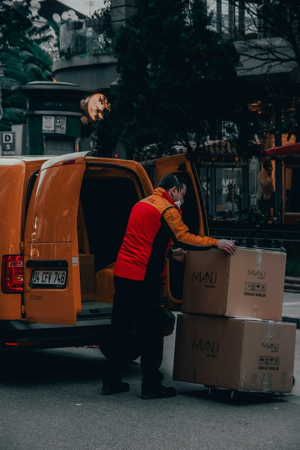 Kurir pengiriman memuat paket dari van — tim lapangan logistik